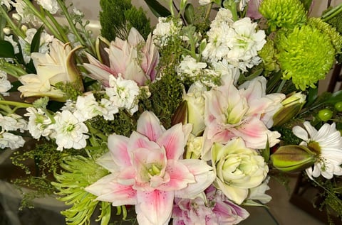 Colorful bouquet of pink lilies, white carnations, and green chrysanthemums with mixed greenery in an arrangement